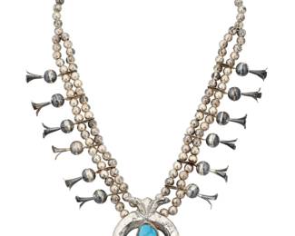 2123 A Southwest silver and turquoise squash blossom necklace Early 20th century Unmarked A double strand of silver beads with twelve blossoms suspending a large cast sterling silver naja, with a later-added turquoise stone to center 24.75" L x 2.75" H 168.4 grams gross Estimate: $700 - $900