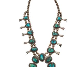 2119 A Mark Chee Navajo silver and turquoise squash blossom necklace Mark Chee (1914-1981, Diné) Mid/late 20th century Etched: M. Chee / Navajo A chunky double strand necklace with ten graduated set turquoise blossoms, suspending a large central stone-set two-wire naja 24.5" L x 3" H 146.8 grams gross Estimate: $1,500 - $2,500
