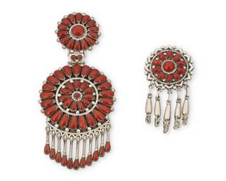 2073 Two Zuni Pueblo cluster set coral pendants Late 20th century Two works: Lorraine Waatsa (b. 20th century, Zuni Pueblo) A large Zuni cluster set petit point coral pendant Stamped: LW A double rosette articulated pendant with set coral dangles 4" H x 1.875" H Lee and Mary Weebothee (1927-2015, and 1934-1995, Zuni Pueblo) A small Zuni cluster set petit point coral pendant/brooch Stamped: Lee/Mary / Zuni A single rosette shield pendant/brooch with silver dangles 2.125" H x 1.125" W 2 pieces 39.2 grams gross Estimate: $300 - $500