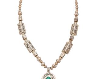 2193 An R. Wylie Navajo sterling silver and malachite pendant necklace R Wylie (b. 20th century, Diné) Late 20th/21st century Stamped: R. Wylie / Sterling A chunky necklace of silver 'pearls,' barrel beads, and long triangular beads with geometric silver overlay, suspending an oval pendant with central set malachite cabochon and silver overlay motifs 27.75" L x 3" H 105.7 grams gross Estimate: $300 - $500