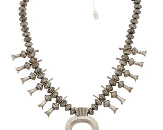 2125 A James McCabe Navajo silver Mercury dime squash blossom necklace James A. McCabe (b. 20th century, Diné) Stamped to hangtag: James A McCabe / Navajo A long chunky single strand Mercury head dime squash blossom necklace with twelve silver blossoms and a sand cast naja 31.25" L x 3.375" H 432.7 grams gross Estimate: $800 - $1,200