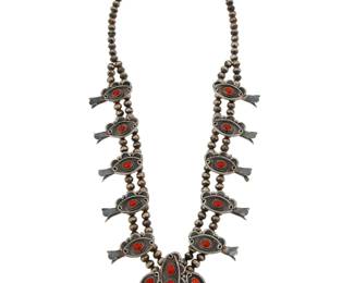 2118 A Southwest sterling silver and coral squash blossom necklace Mid-20th century Unmarked A double strand necklace with ten blossoms each with a set coral cabochon, suspending a matching naja with set coral 28" L x 2.75" H 186.0 grams gross Estimate: $600 - $800