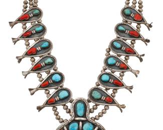 2120 A Herbert Platero Navajo sterling silver and set stone squash blossom necklace Herbert Platero (b. 20th century, Diné) Mid-20th century Etched verso: HP [conjoined] A heavy gauge cast silver triple strand necklace with twelve graduated shadowset turquoise and coral blossoms and a large set stone naja, all with stampwork edge accents 28" L x 3.75" H 328.1 grams gross Estimate: $1,000 - $1,500