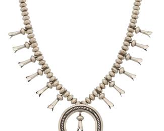 2124 A Southwest sterling silver squash blossom necklace Early/mid-20th century Unmarked A single strand of chunky ridged silver beads with twelve blossoms, and a set turquoise naja with blossom dangle 23.5" L x 2.625" H 207.4 grams Estimate: $800 - $1,200