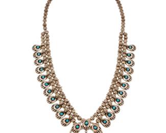 2132 A Southwest sterling silver and turquoise 'Bear Paw' squash blossom necklace Mid/late 20th century Unmarked A delicate necklace with twenty-two petite bear paw 'blossoms' with shadowbox set turquoise and a central naja with a central bear paw dangle, all on a double strand of silver beads 26.25" L x 2" H 84.6 grams gross Estimate: $500 - $700