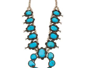 2128 A Southwest sterling silver and turquoise squash blossom necklace Mid-20th century Unmarked A chunky double strand necklace with ten slightly graduated set turquoise blossoms with scallop edging, suspending a large central set stone naja 26" L x 3.5" H 233.6 grams gross Estimate: $700 - $900