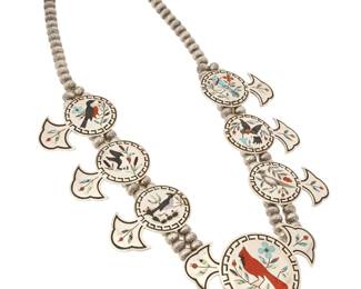 2065 A Dennis & Nancy Edaakie Zuni sterling silver and stone inlay pictorial bird necklace Dennis & Nancy Edaakie (1931-2008 and b. 1937, Zuni Pueblo) Late 20th century Stamped for each verso A large chunky necklace with six multistone inlay 'blossoms' and a central 'naja' each featuring a different bird and flora including a cardinal, roadrunner, duck, robin, Stellar jay, hummingbird, and pheasant, worked in various stones including turquoise, jet, mother of pearl, abalone, and coral, and all mounted to a double strand of stamped silver beads 29.5" L x 2.25" H 264.2 grams gross Estimate: $1,500 - $2,500