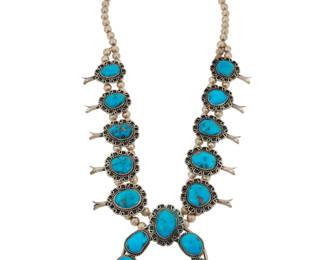 2129 A Southwest silver and turquoise squash blossom necklace Mid-20th century Unmarked A chunky double strand necklace with ten slightly graduated set turquoise blossoms, each with elaborate applied silver wire edging, suspending a large central set stone naja 27" L x 3.5" H 221.5 grams gross Estimate: $700 - $900