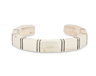 2033 A Nusie Henry Belon Navajo sterling silver cuff bracelet Nusie Henry [Belon] (b. 20th century, Diné) Late 20th century Stamped: Nusie / Sterling A narrow modernist style angled cuff with incised banding details 6" total inner C x 0.375" H, gap: 1" 66.3 grams gross Estimate: $200 - $400