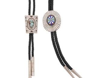 2246 Two Southwest sterling silver bolo ties Late 20th century Two works: Chester Benally (b. 20th century, Diné) A sterling silver and stone inlay bolo Stamped to plaque: C. Benally / Sterling A large feathered concho bolo with central multistone inlay in turquoise, malachite, lapis lazuli, coral and mother of pearl, suspended on a thick black braided leather cord with pointed silver tips Bolo: 2.5" H x 2" W; cord: 47" L A Southwest sterling silver and set turquoise bolo tie Stamped: Keoni / Sterling A silver overlay bolo with stamped feathered center and set teardrop turquoise, all on a black braided leather cord with cylindrical silver tips Bolo: 2" H x 1.5" W; cord: 36" L 2 pieces 140.3 grams gross Estimate: $400 - $600