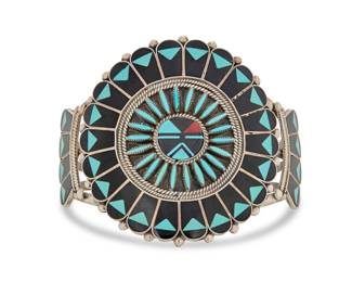2081 A Benjamin and Shirley Tzuni Zuni multistone inlay cuff bracelet Benjamin and Shirley Tzuni (b. 1952 & b. 1941, Zuni Pueblo) Late 20th century With etched signature: Benji Shirly Tzuni / Zuni; stamped: Sterling A large three wire cuff with central Sunface plaque with cluster set needlepoint turquoise and multistone inlay including turquoise and coral 7" total inner C x 2.5" H, gap: 1.75" 53.0 grams gross Estimate: $300 - $500