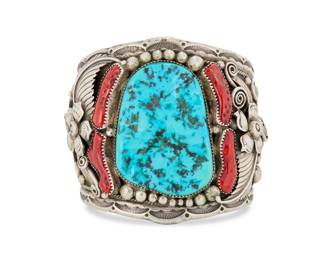 2005 A heavy Southwest sterling silver, turquoise and coral cuff bracelet Mid/late 20th century Unmarked An extra-large gauntlet style wide tapered cuff with a large set slab turquoise, set coral and with elaborate ornate applied silver floral, feather, and ball accents overall, the interior covered with multiple bands of stamped motifs 7.25" total inner C x 2.875" H, gap: 1.25" 224.6 grams gross Estimate: $600 - $800