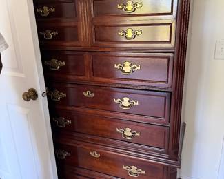 Bassett Furniture highboy dresser features a cherry wood finish and distinctive brass hardware