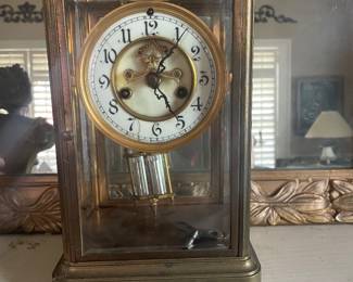 antique Waterbury Clock Co. crystal regulator mantel clock, featuring a brass and glass case housing an enamel dial and a visible faux-mercury pendulum