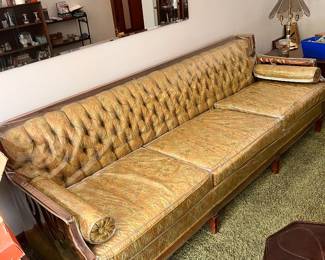vintage Chesterfield-style sofa features button-tufted gold velvet upholstery and decorative wood accents still has plastic 