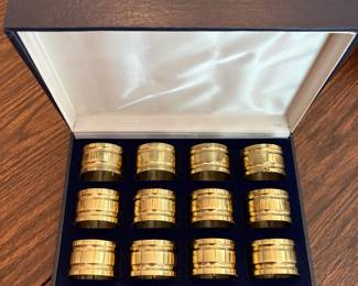 R62 - $20. Set of 12 Brass Napkin Rings in Box. Shows some minor wear.