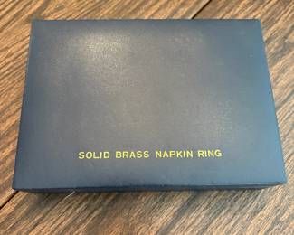 R62 - $20. Set of 12 Brass Napkin Rings in Box. Shows some minor wear.