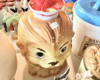Character jar or mug with face and hair detail among table collectibles.