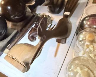 Dark wood horse or animal figure with glass and small collectibles nearby.