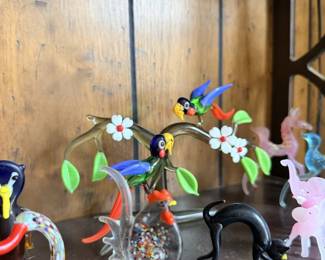 Glass animal menagerie with bright birds, swans, deer and miniature flowers.