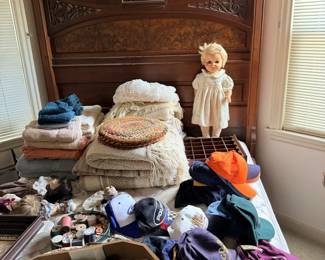 Bedroom table lot with shoes, clothing, textiles and small accessories near wood headboard.