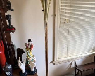 Tall brass-tone floor lamp with nearby figurines and heater.
