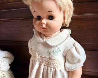 Vintage blonde sleep-eye baby doll in white smocked dress.