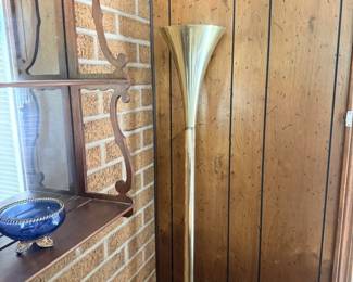 Tall wood-framed floor mirror displayed along brick and wood-paneled wall.