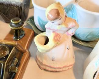 Angel or cherub pitcher/wall pocket with pink bowls and small pottery nearby.