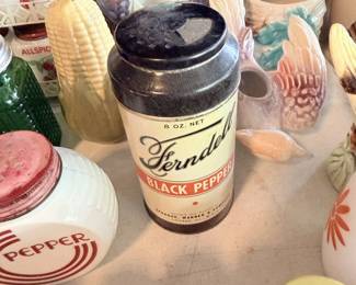 Vintage black pepper tin or jar with colorful kitchen smalls around it.