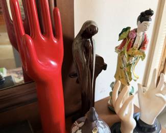Red mannequin hand display, small figures and Asian-style doll grouping.