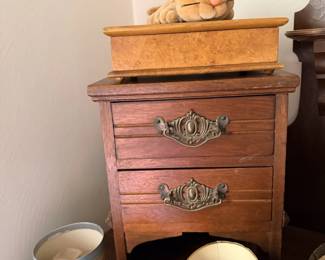 Small carved wood jewelry chest or nightstand with decorative drawer pulls.