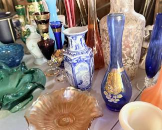 Mixed art glass and pottery tabletop with blue/white vases and amber/peach glass.