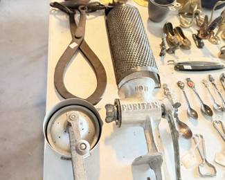 Table of vintage kitchen and garage tools including grinder, scale, corkscrews and utensils.