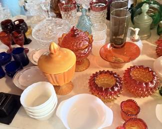 Amber red glass bowls, green bottles, white bowls and pressed-glass serving pieces.