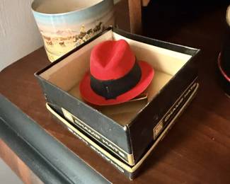 Small red fedora hat on black mirrored or trinket box.