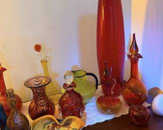 Colorful art-glass vase grouping with tall red vase, orange/red bottles and flower-shaped bowl.