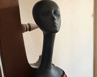 Black mannequin head or hat stand on red base.