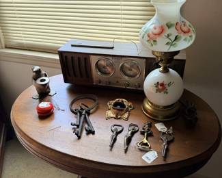 Round table lot with floral lamp, keys, marbles, bottles and small collectibles.