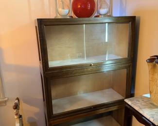 Glass-front display cabinet or shelf unit with clear vases and red accent decor.