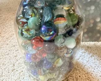 Large jar packed with assorted glass marbles.