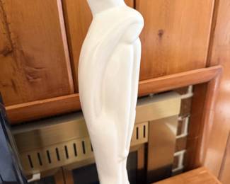 Tall white stylized female figure sculpture.