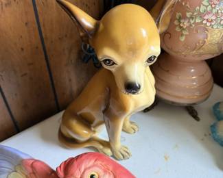 Chihuahua dog figurine plus colorful bird figure and pottery in background.