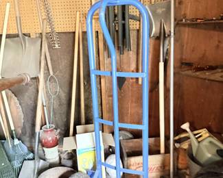 Garage tool corner with hand truck/dolly, shovels, rakes and yard tools.