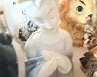 Close-up of white reclining female figurine among small ceramics.