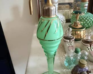 Tall green glass perfume atomizer with brass-tone pump.