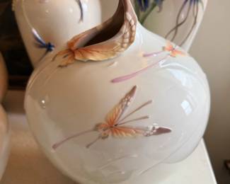 White ceramic vase or jug with dragonfly/floral pattern and ribbon accent.