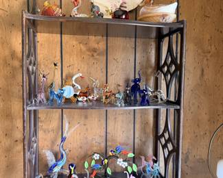 Wall shelf loaded with small animal figures, glass birds and miniature decor.