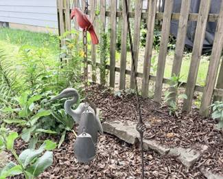 Hanging shepherd hook with red birdhouse/feeder and garden decor.