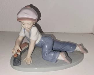 This is Lladró “All Aboard” #7619, boy playing with a toy train. It’s a retired Collectors Society piece, usually around 5" tall x 7" long.
